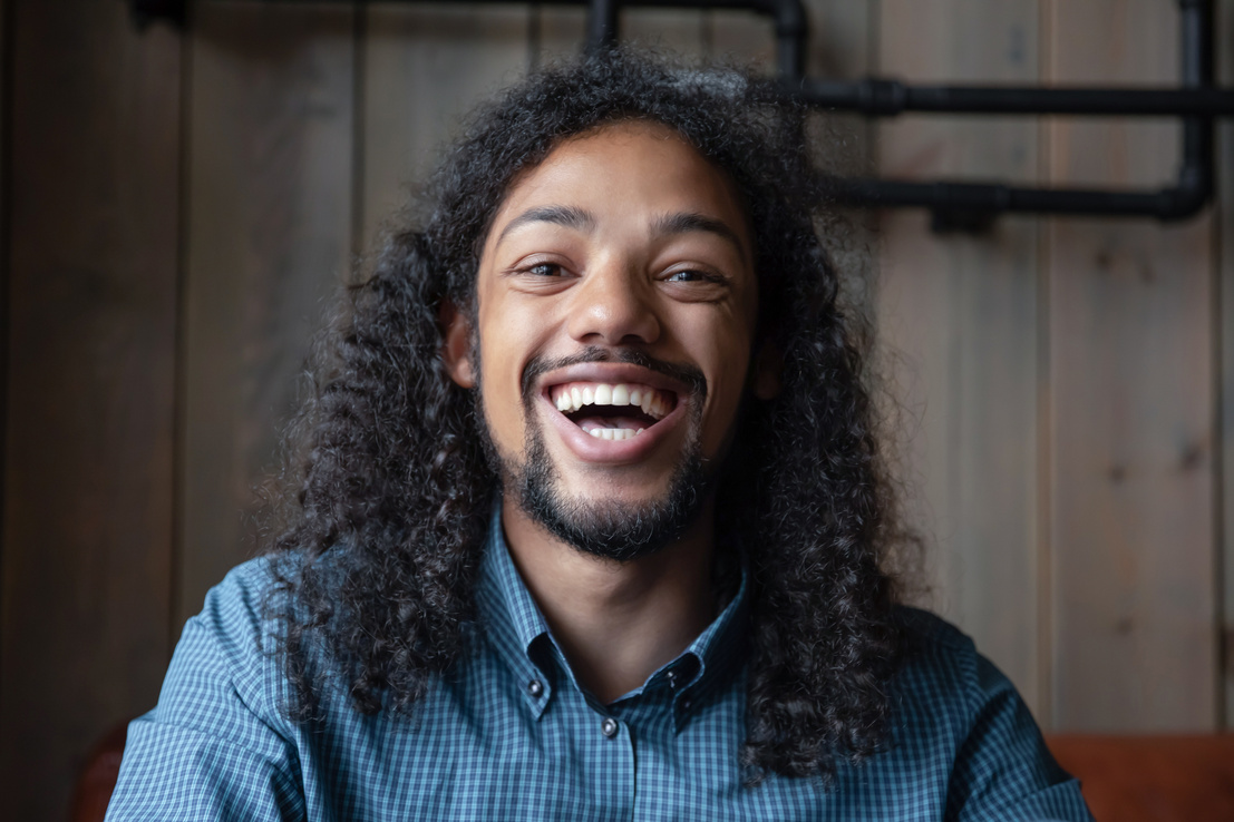 Profile picture of laughing young biracial male looking at camera